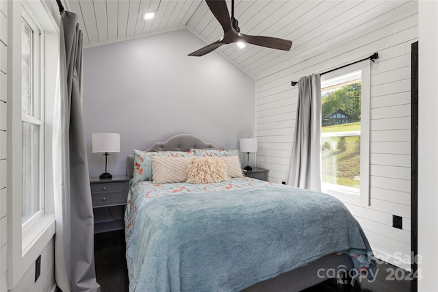 bedroom with vaulted ceiling, wooden ceiling, ceiling fan, and wood walls