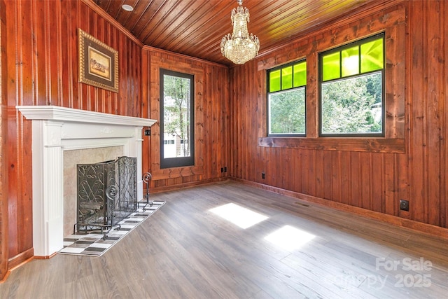 unfurnished living room featuring a chandelier, wood walls, wood ceiling, and a fireplace