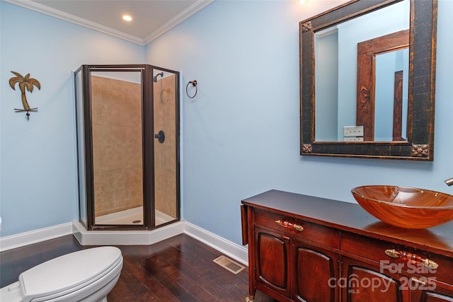 bathroom featuring hardwood / wood-style floors, vanity, toilet, walk in shower, and ornamental molding