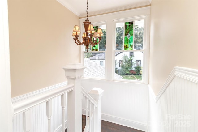 stairs featuring ornamental molding, an inviting chandelier, and wood-type flooring