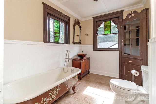 bathroom featuring crown molding, toilet, and a tub to relax in