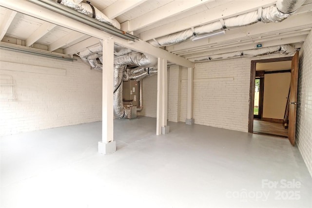 basement featuring heating unit and brick wall