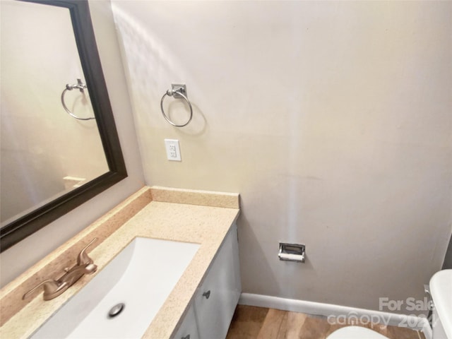 bathroom with vanity, toilet, and hardwood / wood-style floors