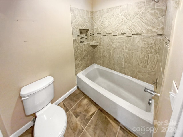 bathroom with tiled shower / bath, tile patterned floors, and toilet