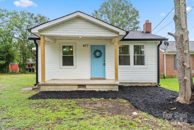 bungalow-style home featuring covered porch, a front lawn, a chimney, and a shingled roof