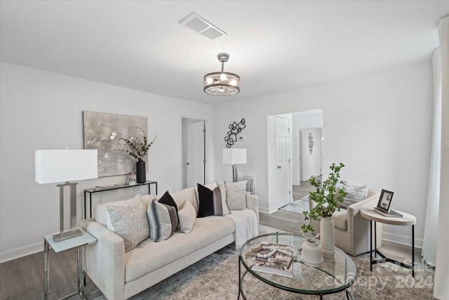 living area featuring baseboards, visible vents, and wood finished floors