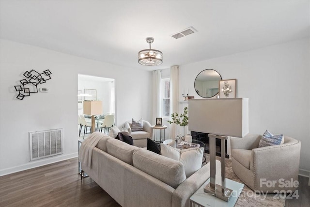 living room with dark wood-style floors, visible vents, and baseboards