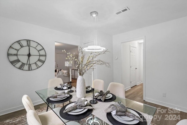 dining area with dark wood-type flooring, visible vents, a notable chandelier, and baseboards