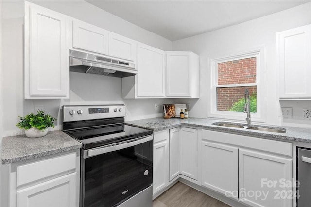 kitchen featuring light stone counters, under cabinet range hood, stainless steel appliances, a sink, and white cabinets