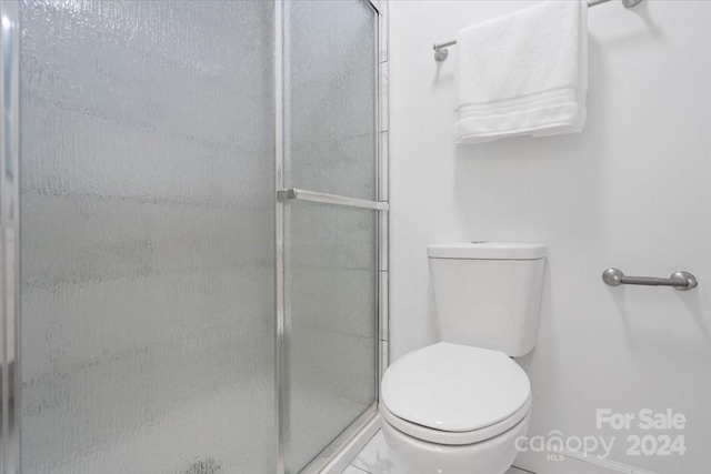 bathroom featuring toilet and an enclosed shower