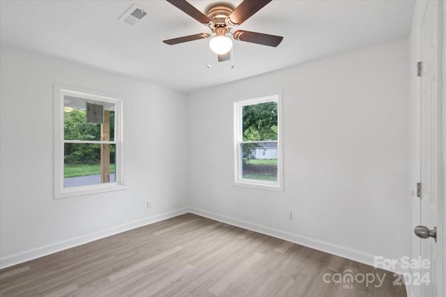 unfurnished room with light wood finished floors, visible vents, and baseboards