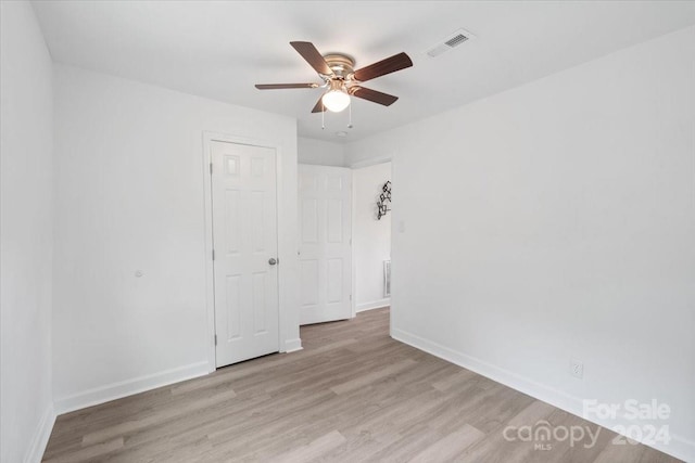 spare room with light wood-type flooring, visible vents, ceiling fan, and baseboards