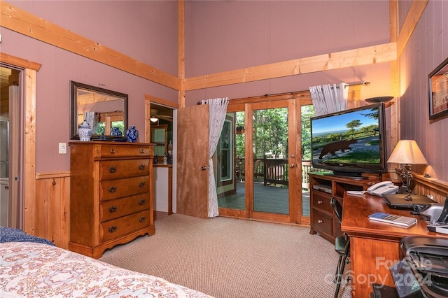 bedroom featuring light carpet, access to outside, wooden walls, and a high ceiling