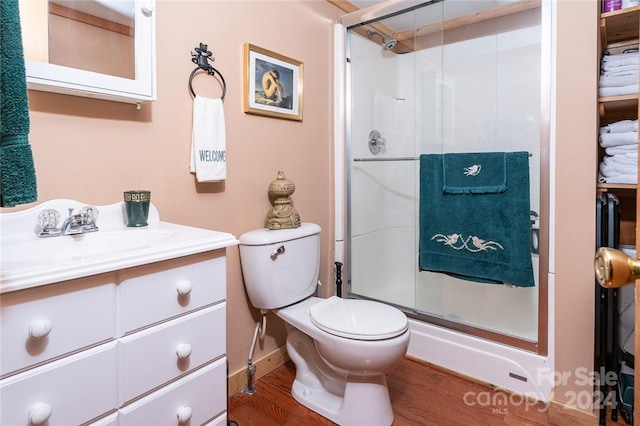 bathroom featuring vanity, wood-type flooring, toilet, and walk in shower