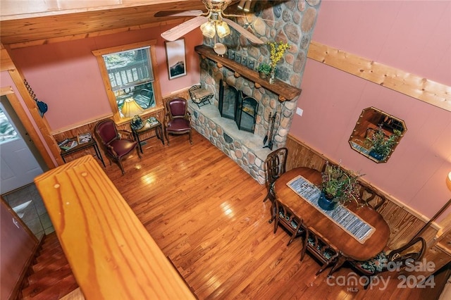 living room with a stone fireplace, wood-type flooring, ceiling fan, and vaulted ceiling