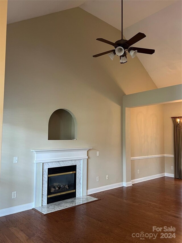 unfurnished living room with dark wood-type flooring, a premium fireplace, high vaulted ceiling, and ceiling fan