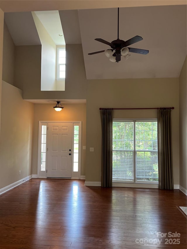 entryway with dark wood-type flooring, ceiling fan, and a high ceiling