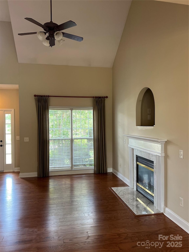 unfurnished living room featuring ceiling fan, a high end fireplace, dark hardwood / wood-style flooring, and high vaulted ceiling