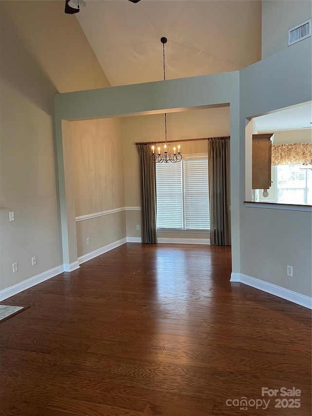 spare room featuring a notable chandelier and dark wood-type flooring