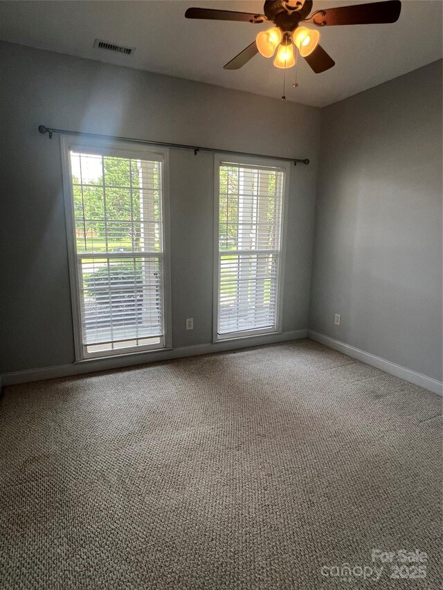 unfurnished room with ceiling fan, carpet, and a wealth of natural light