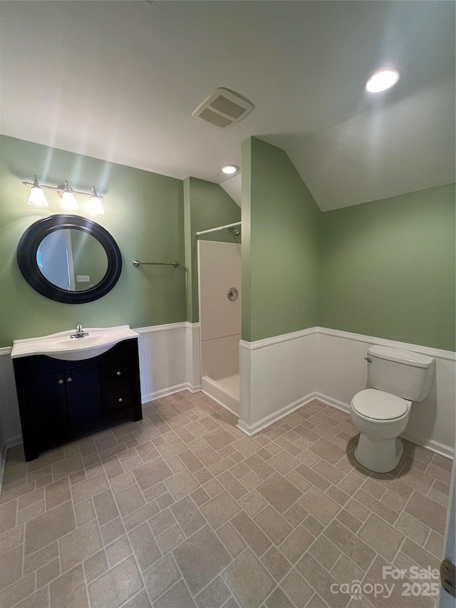 bathroom featuring vanity, lofted ceiling, toilet, and a shower