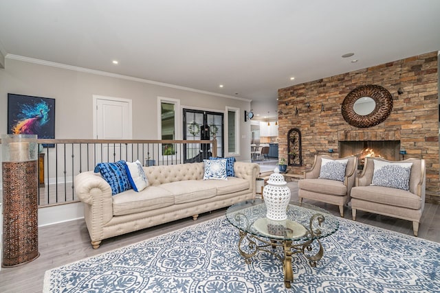 living room featuring a fireplace, ornamental molding, and light wood-type flooring