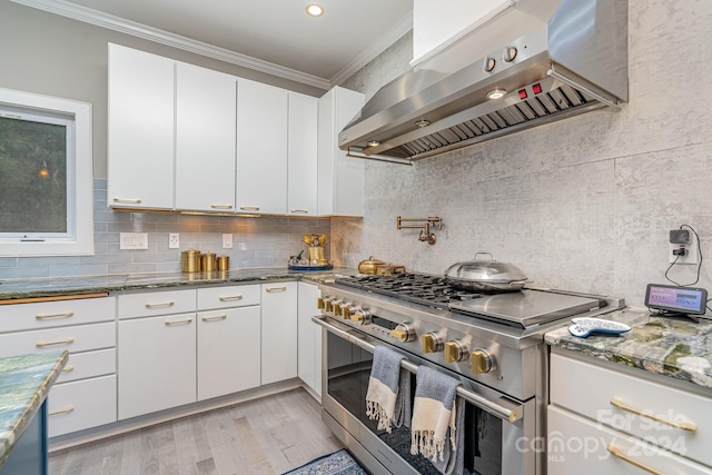 kitchen featuring white cabinets, crown molding, high end stainless steel range, and range hood