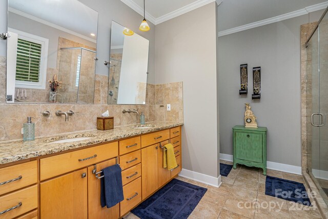 bathroom featuring tile patterned floors, ornamental molding, an enclosed shower, dual bowl vanity, and backsplash