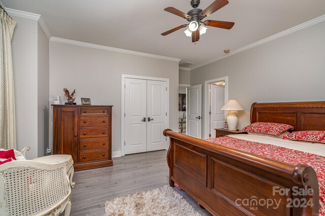 bedroom featuring crown molding, light wood-type flooring, ceiling fan, and a closet