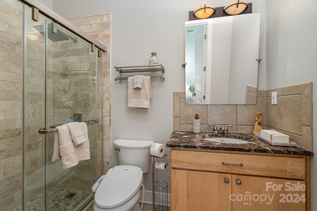 bathroom with tile walls, walk in shower, decorative backsplash, toilet, and vanity