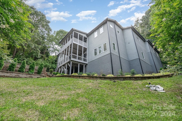 back of house with a sunroom and a lawn