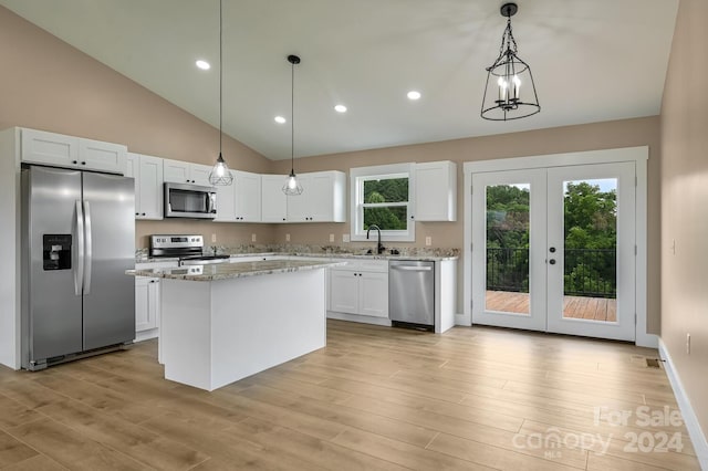 kitchen featuring appliances with stainless steel finishes, hanging light fixtures, light wood-type flooring, a center island, and white cabinetry