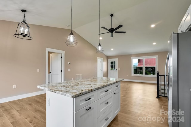 kitchen with ceiling fan with notable chandelier, white cabinets, light wood-type flooring, a kitchen island, and stainless steel fridge