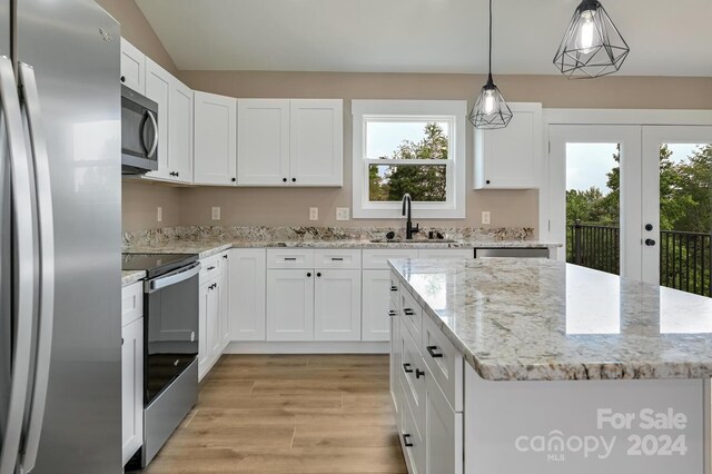 kitchen with stainless steel appliances, hanging light fixtures, light hardwood / wood-style floors, a kitchen island, and white cabinetry