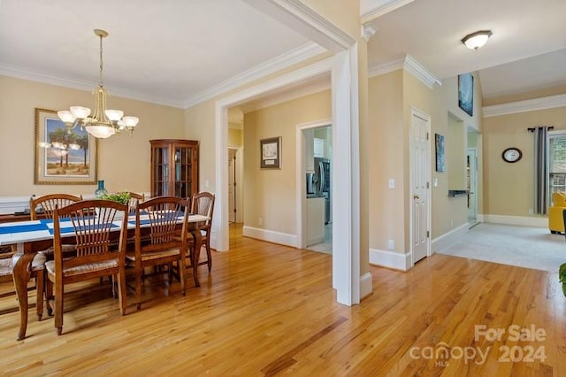 dining area with light hardwood / wood-style floors, a chandelier, and ornamental molding