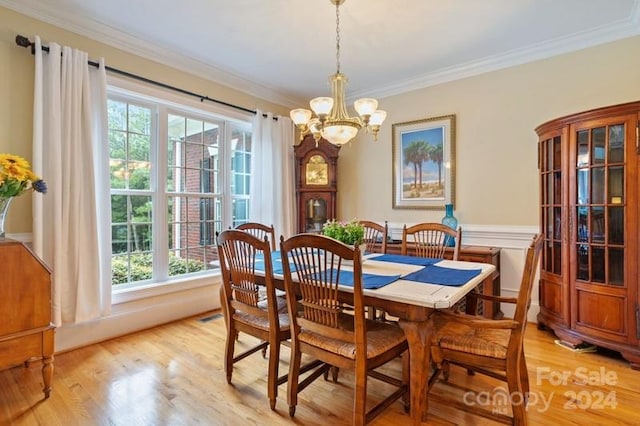 dining room with an inviting chandelier, light hardwood / wood-style floors, crown molding, and plenty of natural light