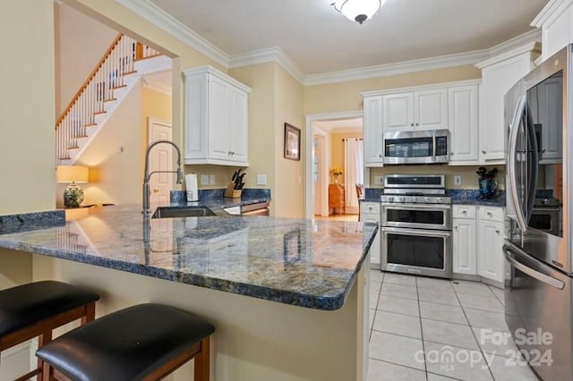 kitchen featuring light tile patterned floors, kitchen peninsula, white cabinets, appliances with stainless steel finishes, and ornamental molding