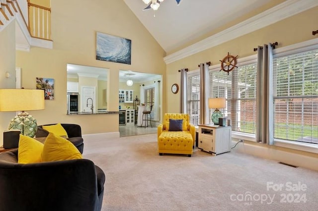 carpeted living room with ornamental molding, ceiling fan, and high vaulted ceiling