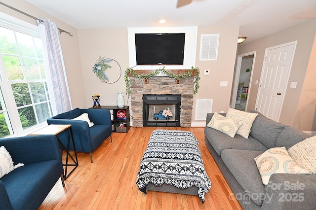 living room with a stone fireplace and wood-type flooring