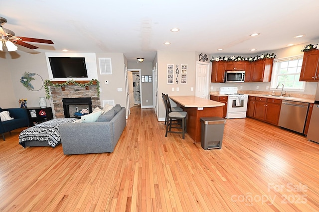 kitchen featuring a breakfast bar, sink, light wood-type flooring, appliances with stainless steel finishes, and a kitchen island