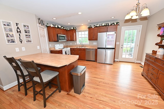 kitchen featuring decorative light fixtures, sink, a kitchen breakfast bar, light hardwood / wood-style floors, and stainless steel appliances