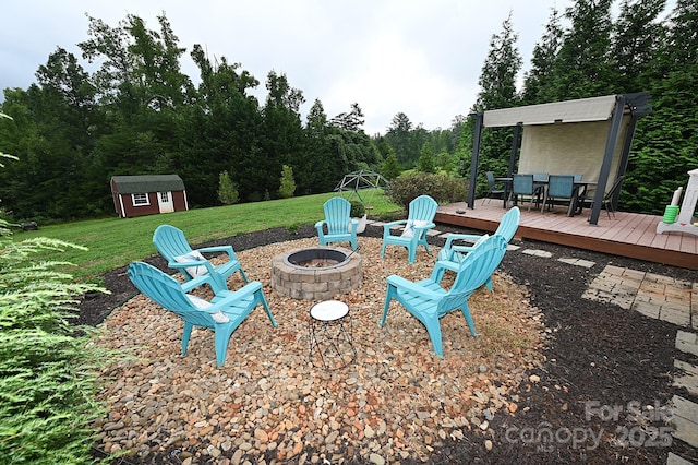 view of yard featuring a wooden deck, a storage unit, and a fire pit