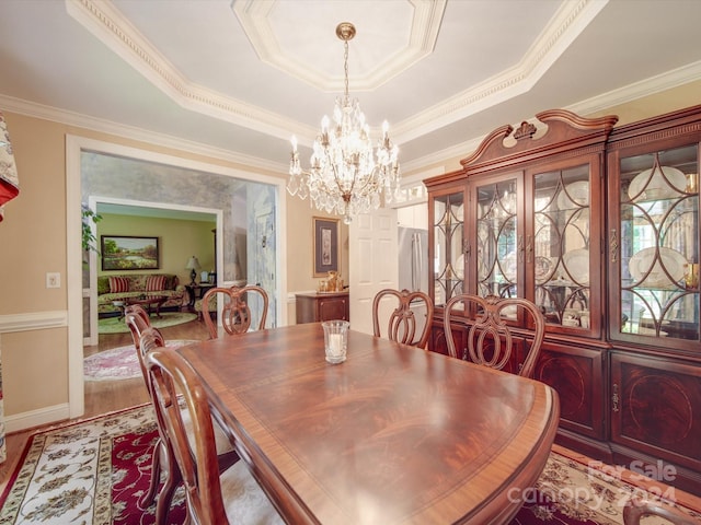 dining area with a notable chandelier, crown molding, and a tray ceiling