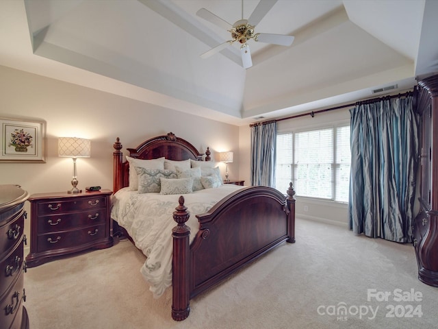 carpeted bedroom featuring ceiling fan and a tray ceiling