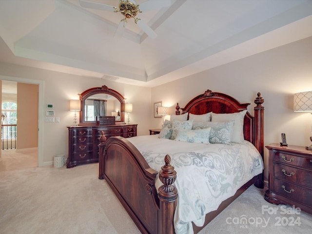 bedroom featuring a tray ceiling, light carpet, and ceiling fan