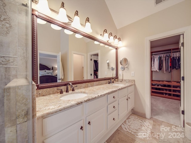 bathroom with dual vanity, lofted ceiling, and tile patterned flooring