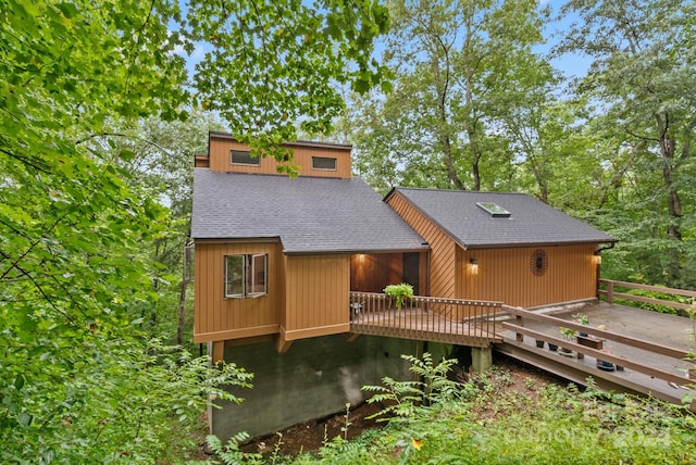 view of front of home with a wooden deck and roof with shingles