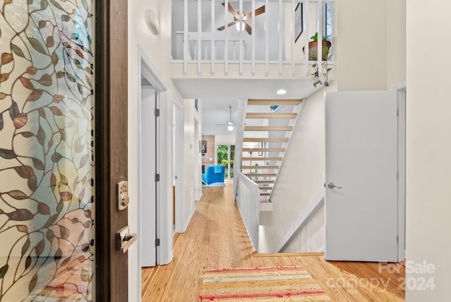 entryway with ceiling fan, wood finished floors, and a towering ceiling