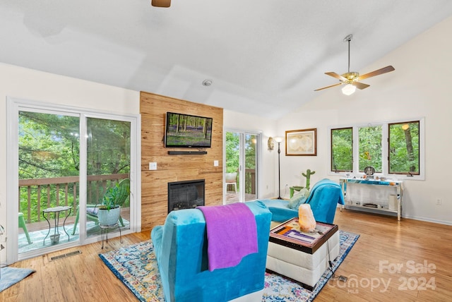 living area with a fireplace, visible vents, a ceiling fan, wood finished floors, and high vaulted ceiling