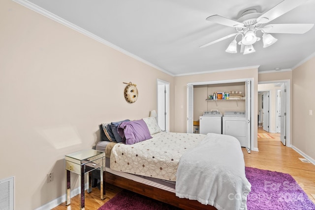 bedroom with crown molding, washing machine and clothes dryer, visible vents, wood finished floors, and baseboards